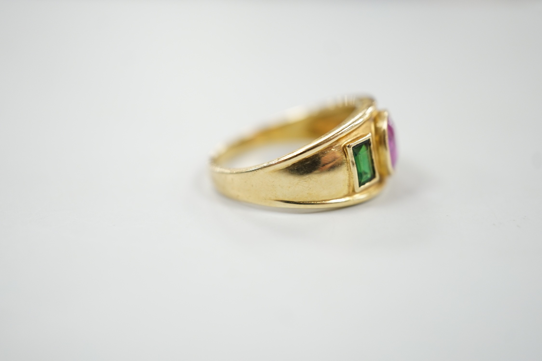 A modern 14k, collet set ruby and green paste? three stone ring, size L, gross weight 4 grams.